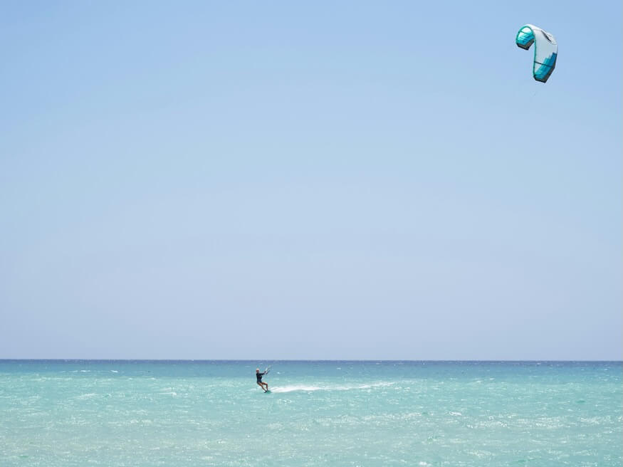 person in body of water kiteboarding during daytime