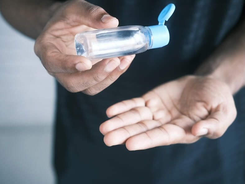 person holding clear glass bottle with blue lid