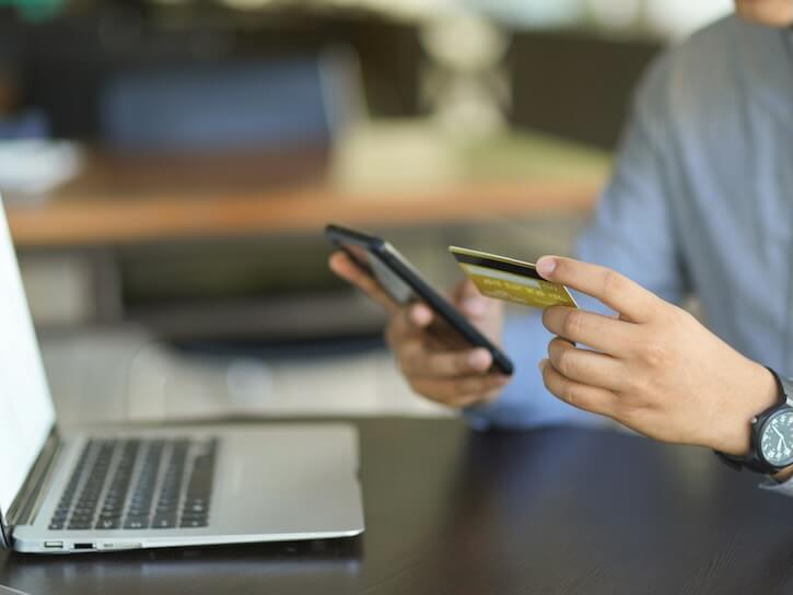 cropped image of a man or businessman holding credit card and smartphone at his desk internet online banking concept