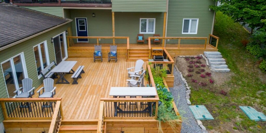 a deck with chairs and tables on it next to a house FEATURED IMAGE