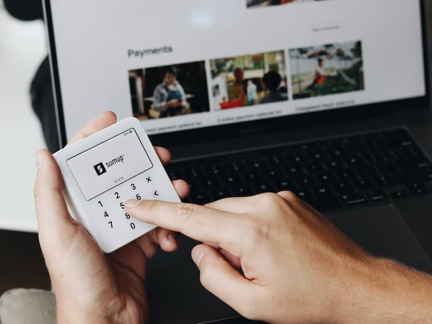 a person holding a remote control in front of a laptop 
