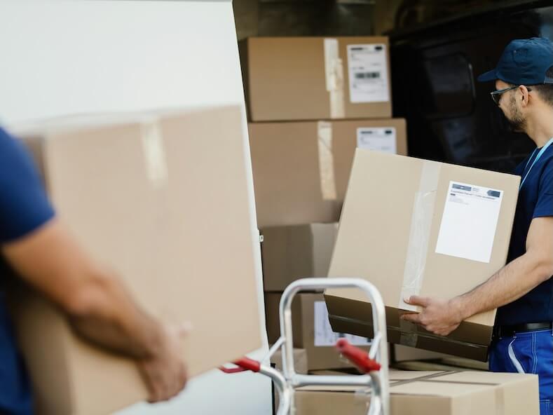 delivery man carrying cardboard boxes and loading them in a mini-van