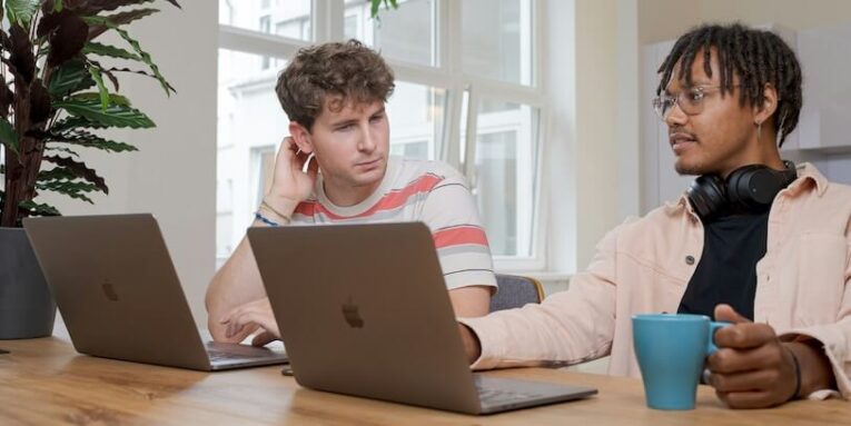 two men sitting at table using MacBook featured image