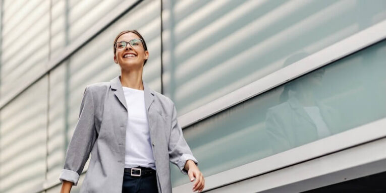 a happy young business woman with a smile on her face walking outside going to her office FEATURED IMAGE
