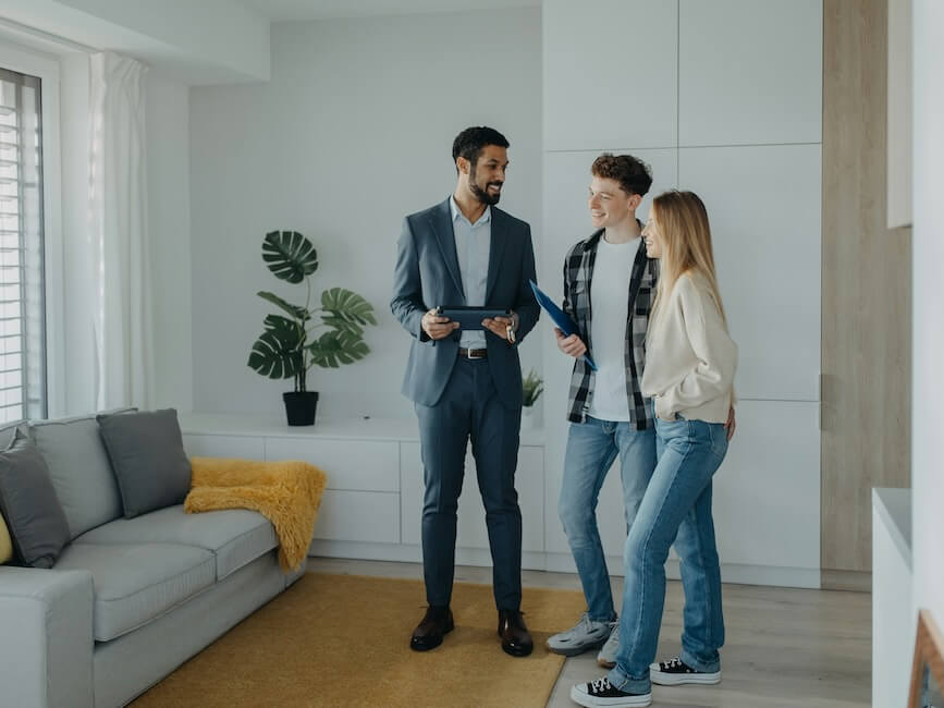 a happy young couple buying their new home and meeting real estate agent in apartment