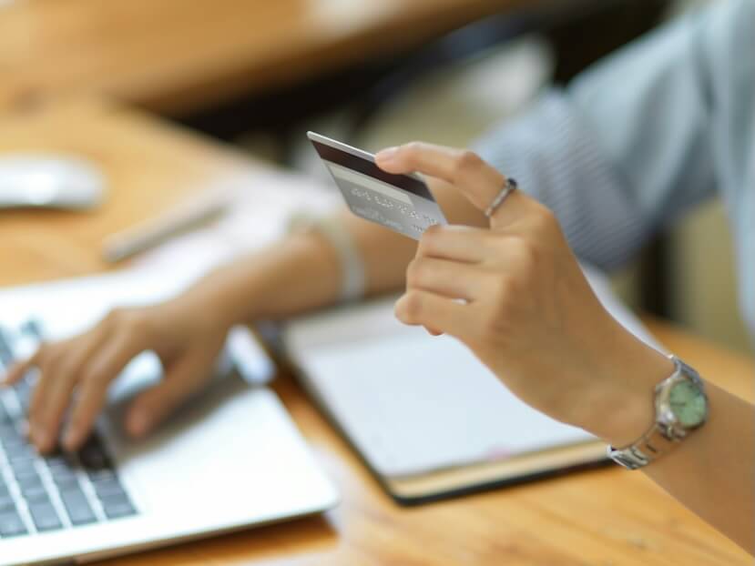 cropped and close up image a female in formal suit using laptop computer and holding a credit card over worktable credit card payment