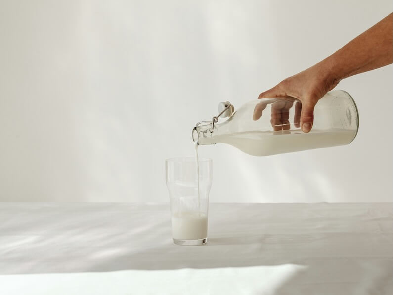a person is pouring milk into a glass
