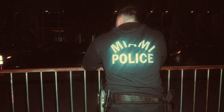 a police officer standing next to a fence FEATURED IMAGE