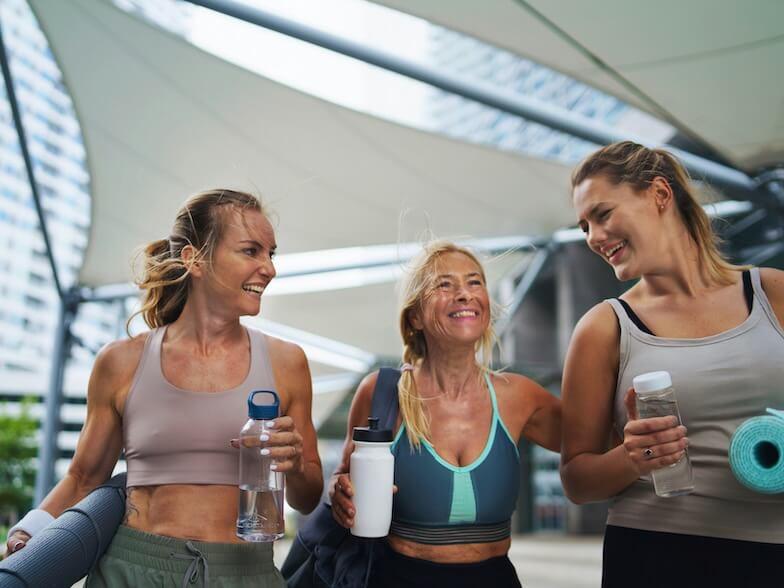 a group of young and old women walking after exercise outdoors in city talking