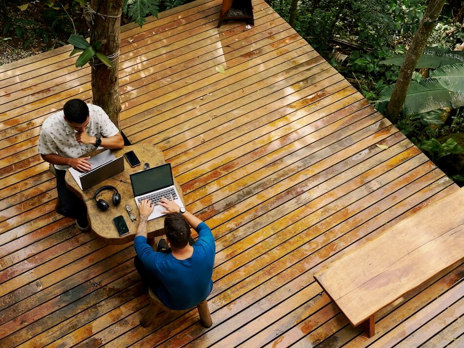 two people sitting at a table on a wooden deck