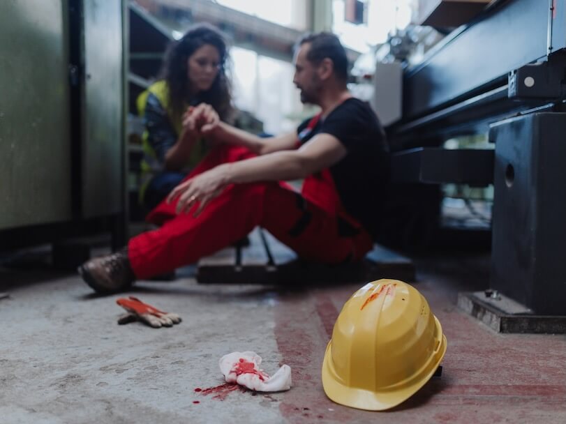 a woman is helping her colleague after accident in factory first aid support on workplace concept