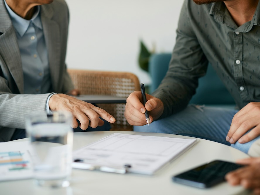 close up of couple closing a deal with their financial advisor and signing paperwork during the meeting
