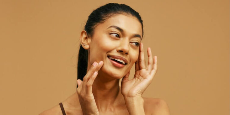 a woman is smiling and touching her face FEATURED IMAGE