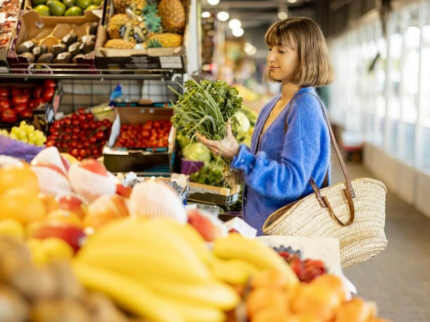 young woman buying greens at local market shopping fresh local raw food sustainability and organic local food concept