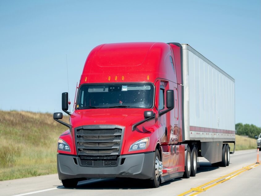 a red semi-truck driving down a highway