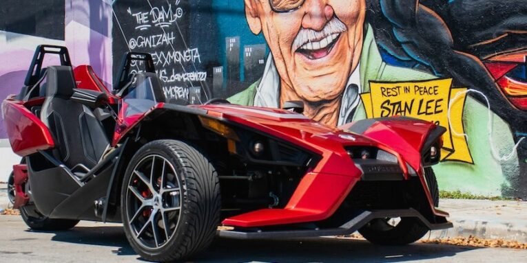 red and black sports car beside wall FEATURED IMAGE