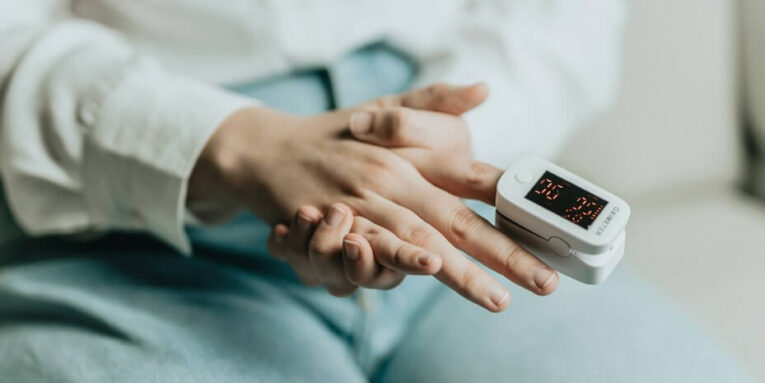 a person sitting on a couch holding an electronic device FEATURE IMAGE