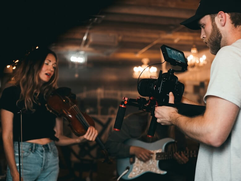 man taking video of woman holding violin