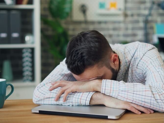 a man sitting at a desk with his head in his hands