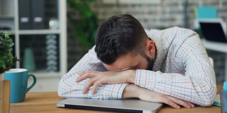 a man sitting at a desk with his head in his hands FEATURED IMAGE