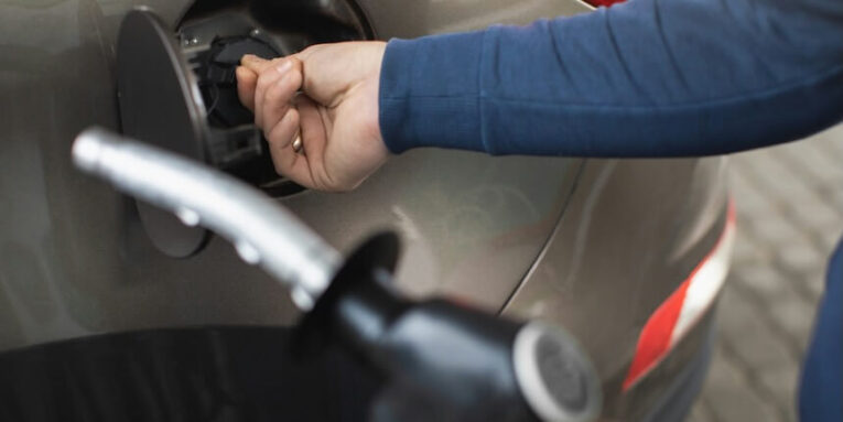 close up cropped image of male hands holding filling gun and opening fuel tank of his luxury car ready to refueling the car at petrol station FEATURED IMAGE
