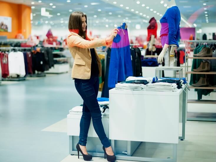 attractive woman choosing cloths in shop