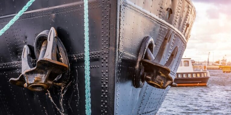 the nose and anchors of a black icebreaker moored in the port FEATURED IMAGE