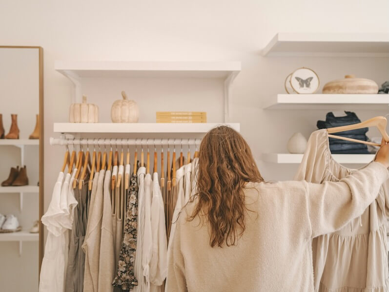 a woman standing in front of a rack of clothes