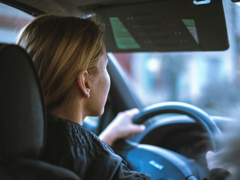 a woman sitting in a car with a steering wheel