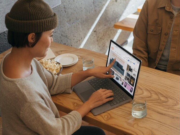 two people sitting across from each other in an office working on a surface laptop
