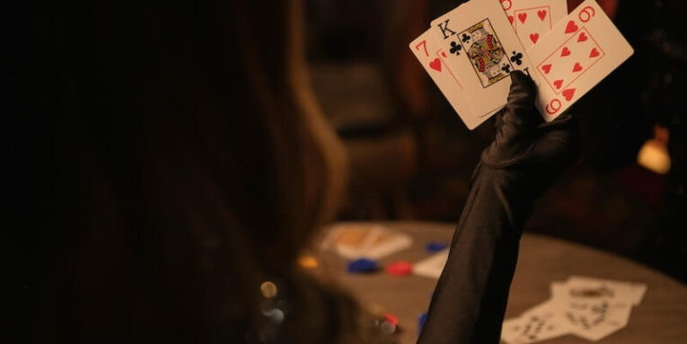 a person holding up playing cards on a table FEATURED IMAGE