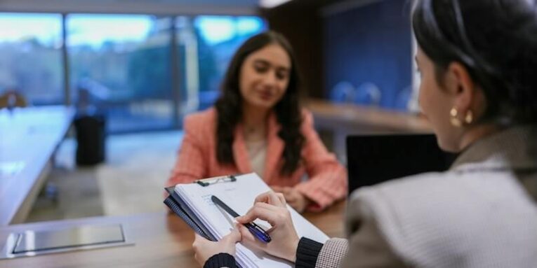 a woman sitting at a desk with a notebook in front of her FEATURED IMAGE