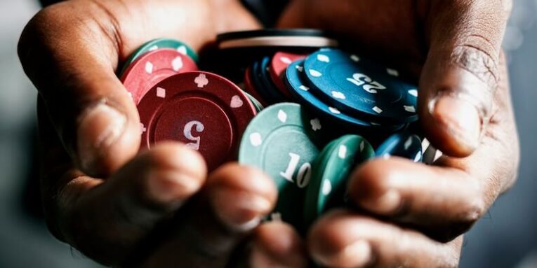 black hands holding gambling chips FEATURE IMAGE