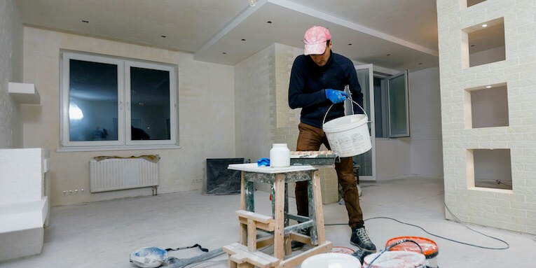 a young man at work painter with a brush concept of repair FEATURED IMAGE