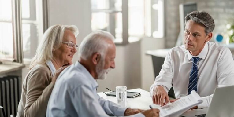 senior couple signing a contract while being on a meeting with bank manager focus is on manager FEATURED IMAGE