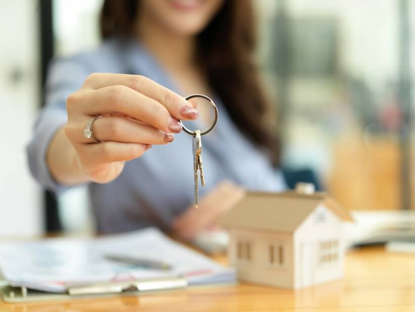 female residential broker real estate agent holding house keys in hand property investment concept