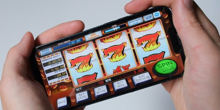 someone is playing a mobile slot machine game FEATURED IMAGE