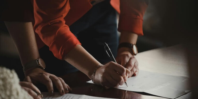 person in orange long sleeve shirt writing on white paper FEATURED IMAGE