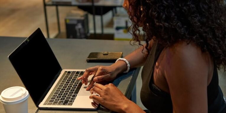 a woman sitting at a table using a laptop computer FEATURED IMAGE