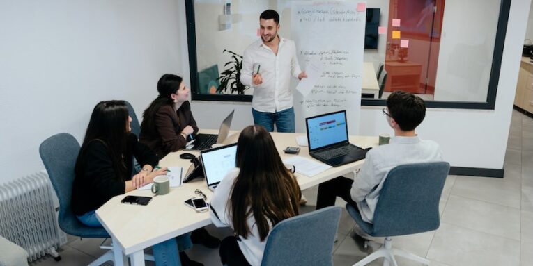 a group of people sitting around a table with laptops FEATURED IMAGE