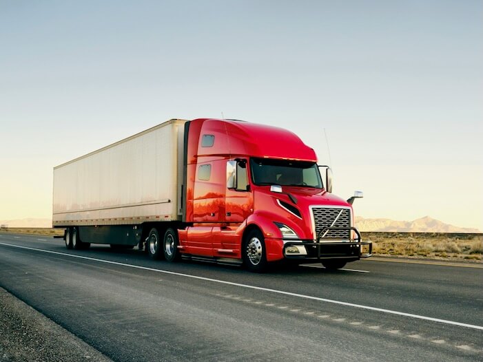 large semi truck hauling freight on the open highway in the western usa under a morning sky