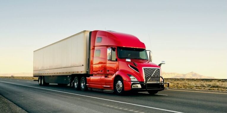 large semi truck hauling freight on the open highway in the western usa under a morning sky FEATURED IMAGE