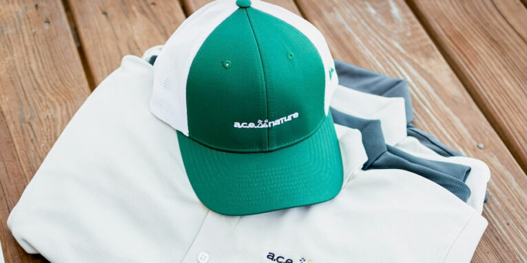 a green and white hat sitting on top of a white shirt FEATURED IMAGE