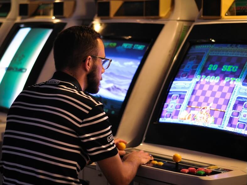 man in black and white striped shirt playing arcade game