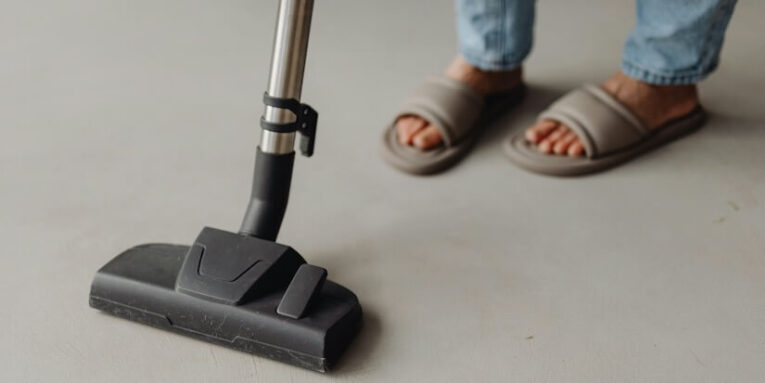 a person standing on a floor with a vacuum FEATURED IMAGE