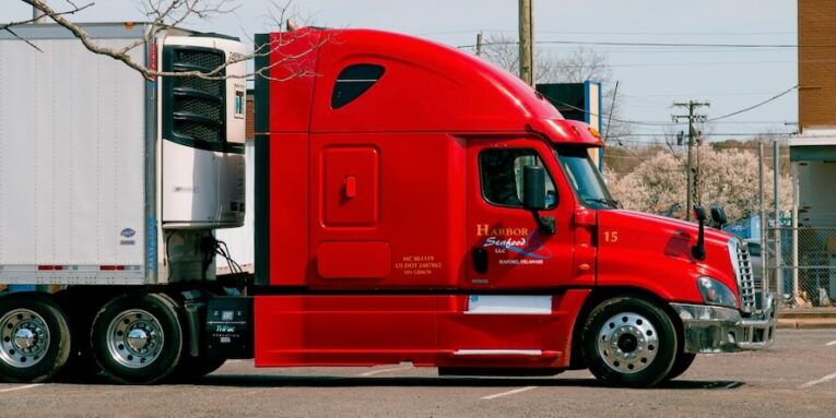 red and white truck on road during daytime FEATURED IMAGE