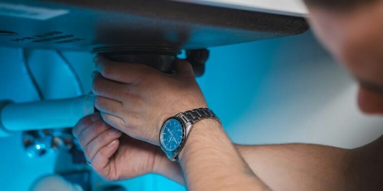 a man fixing a water heater in a room FEATURE IMAGE