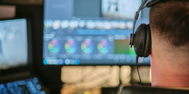 a man wearing headphones sitting in front of a computer monitor FEATURED IMAGE