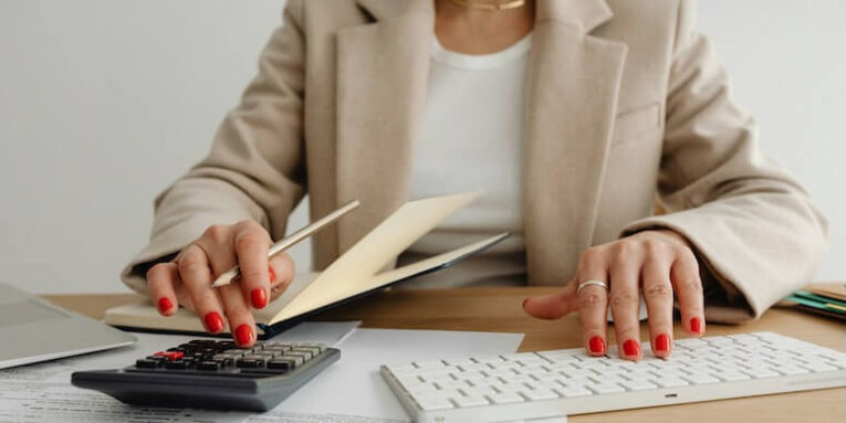 woman sitting at a desk with a calculator FEATURED IMAGE