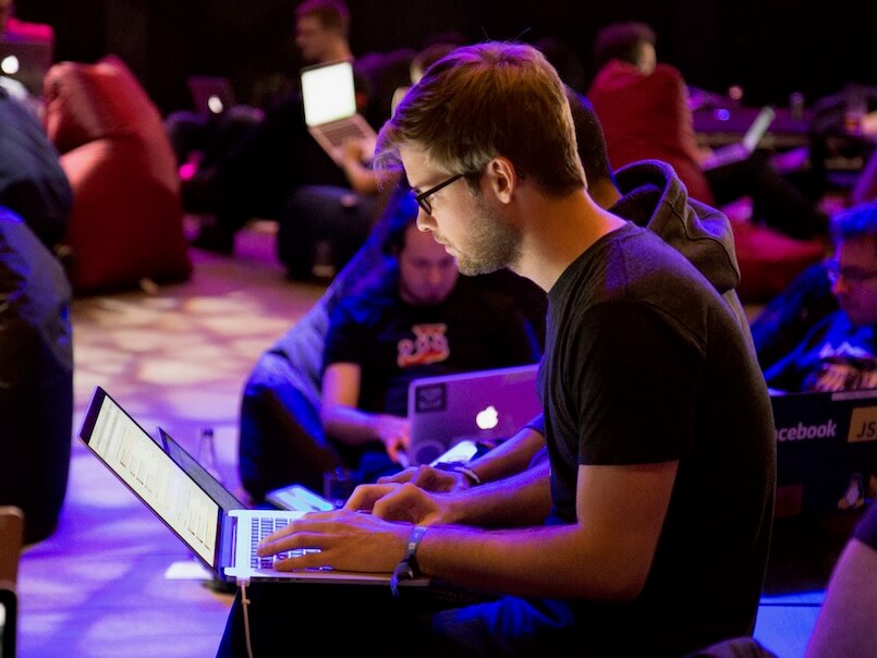man using laptop in front of brown chair